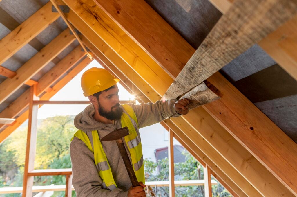Attic insulation contractor installing insulation between roof rafters in Langley BC home